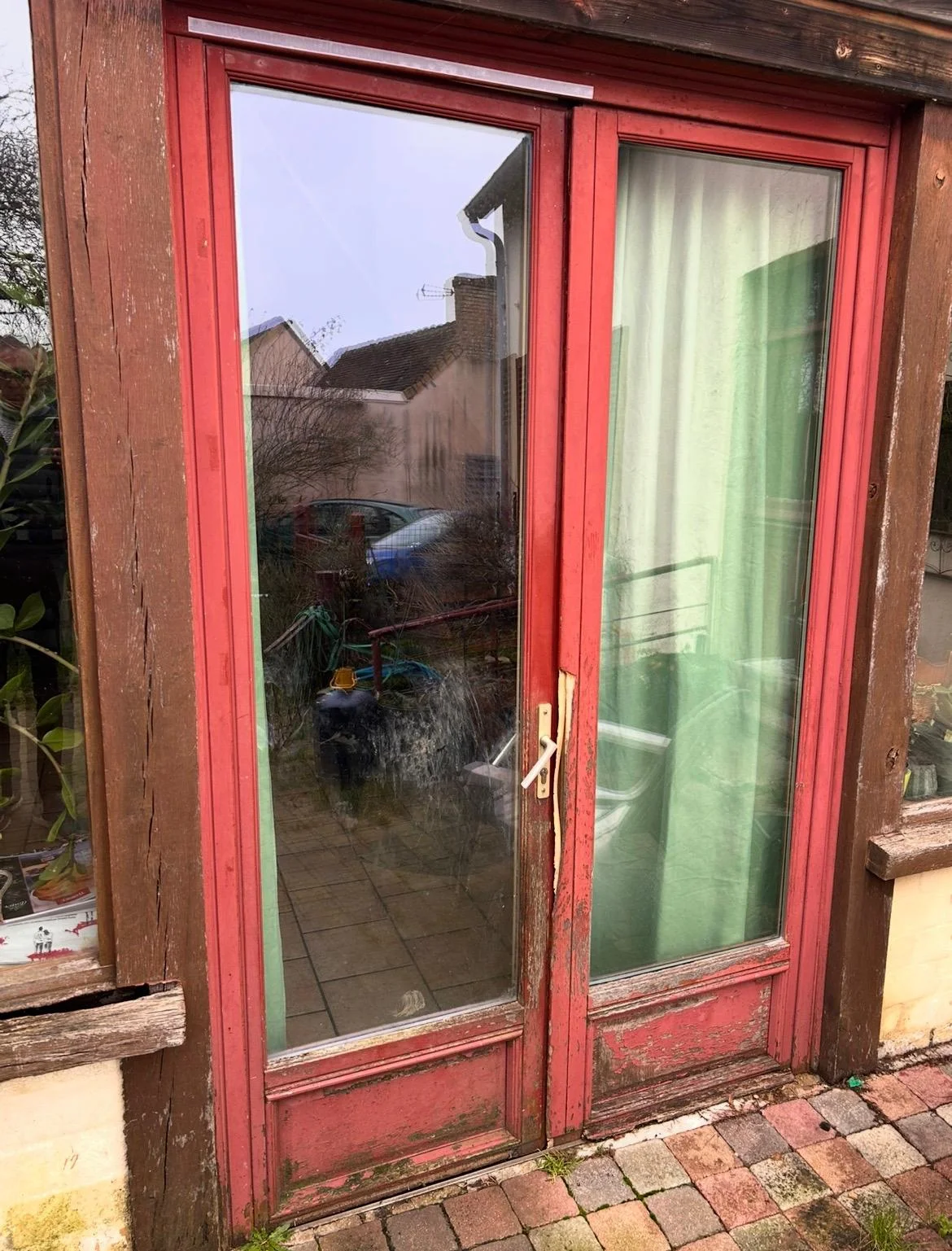 Ancienne porte-fenêtre en bois à la peinture écaillée avant remplacement au Mans